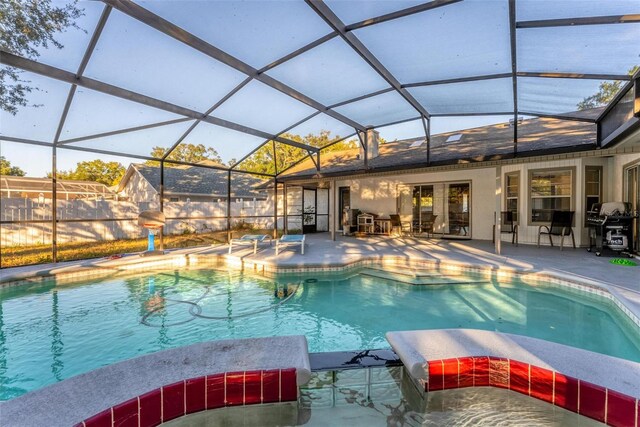 view of pool featuring a patio, glass enclosure, and a grill