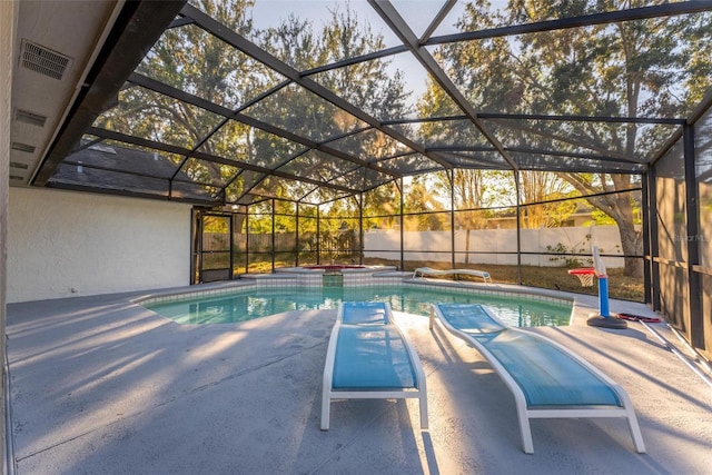 view of swimming pool with glass enclosure, an in ground hot tub, and a patio area