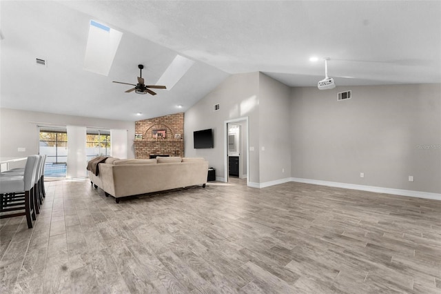 living room with light hardwood / wood-style flooring, ceiling fan, and vaulted ceiling with skylight