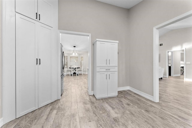 hallway featuring light hardwood / wood-style floors and high vaulted ceiling