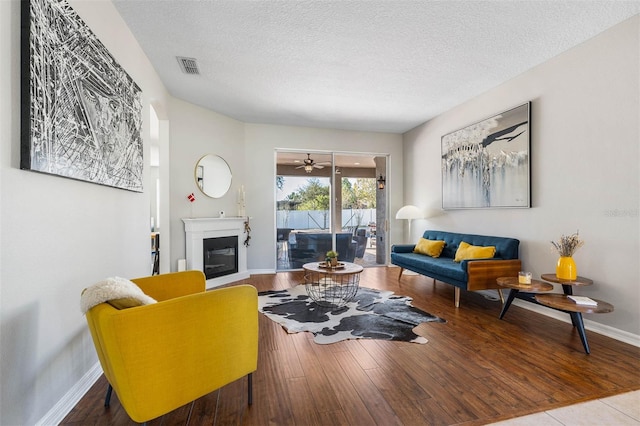 living room with ceiling fan, hardwood / wood-style floors, and a textured ceiling