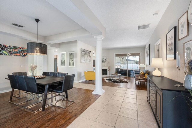 dining space with ornate columns, light tile patterned floors, and a textured ceiling