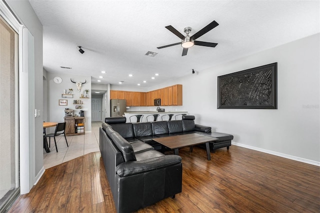 living room featuring a textured ceiling, light hardwood / wood-style flooring, and ceiling fan