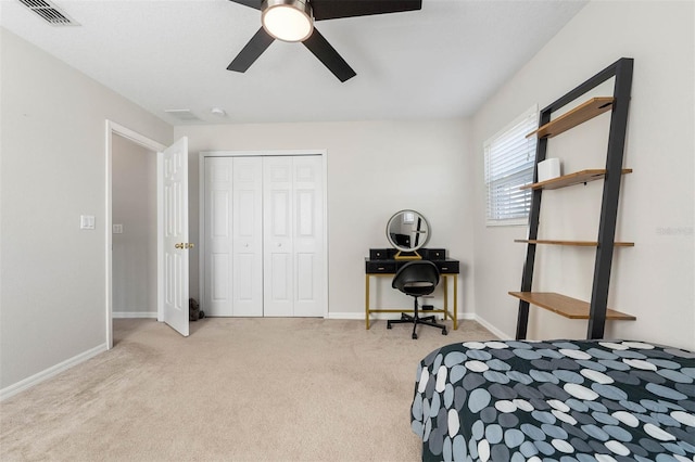 bedroom with ceiling fan, light carpet, and a closet