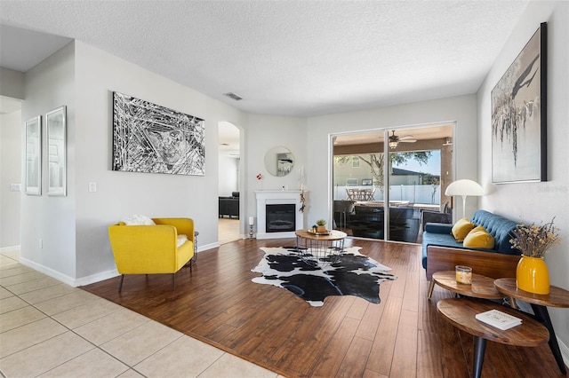 tiled living room featuring ceiling fan and a textured ceiling