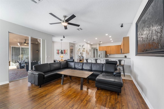 living room with wood-type flooring, a textured ceiling, and ceiling fan