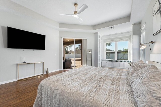 bedroom with access to exterior, a raised ceiling, ceiling fan, and dark wood-type flooring