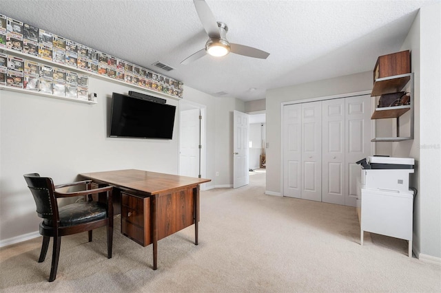 carpeted office space with a textured ceiling and ceiling fan