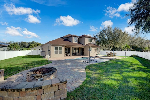 back of property with a yard, a fenced in pool, a fire pit, and a patio area