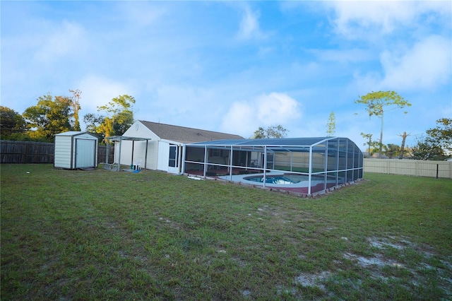 rear view of property with a fenced in pool, glass enclosure, a yard, and a storage shed