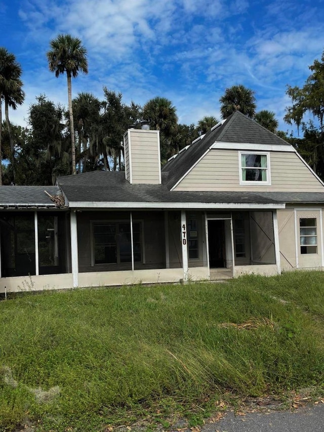 rear view of house with a sunroom and a lawn