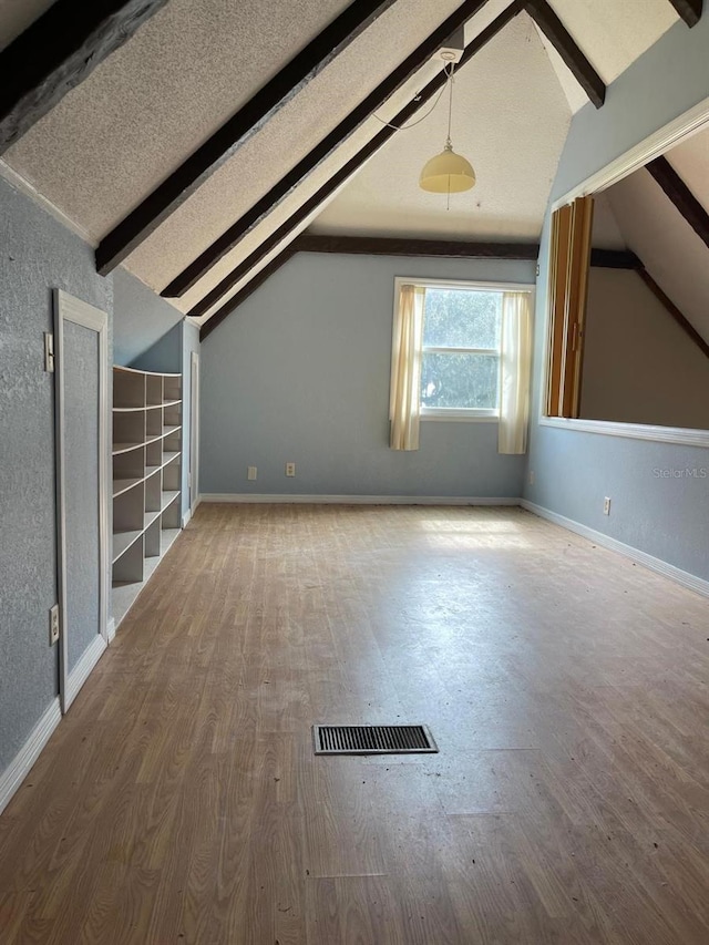 bonus room with lofted ceiling with beams and hardwood / wood-style flooring