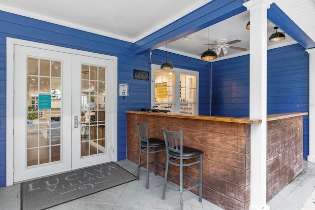 bar with wooden walls, french doors, ceiling fan, and hanging light fixtures