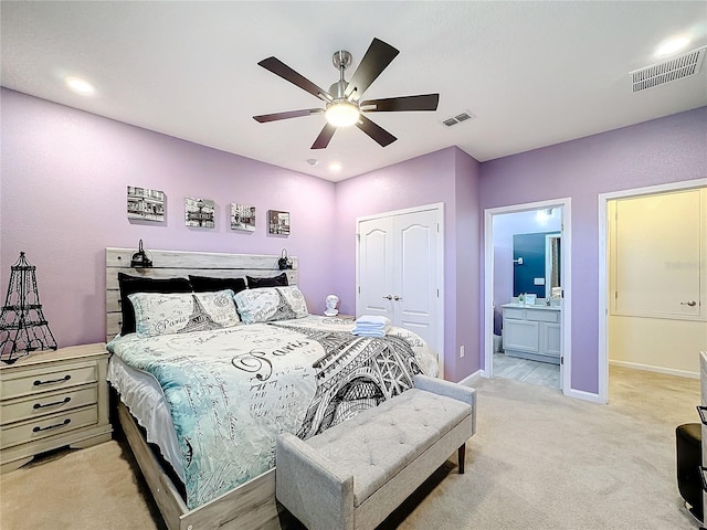 bedroom with connected bathroom, light carpet, a closet, and ceiling fan