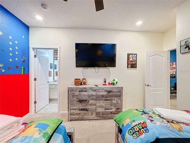 bedroom featuring light carpet, ceiling fan, ensuite bathroom, and a textured ceiling