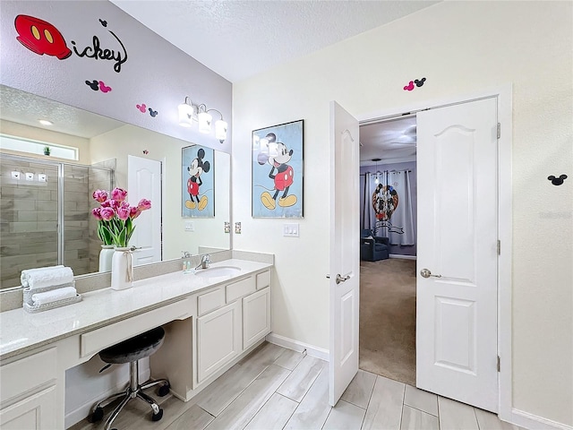 bathroom featuring vanity, a shower with shower door, and a textured ceiling