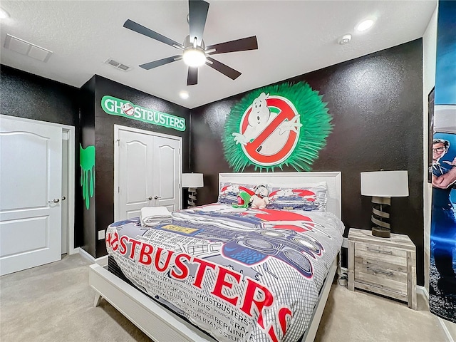 bedroom featuring ceiling fan, a closet, light colored carpet, and a textured ceiling