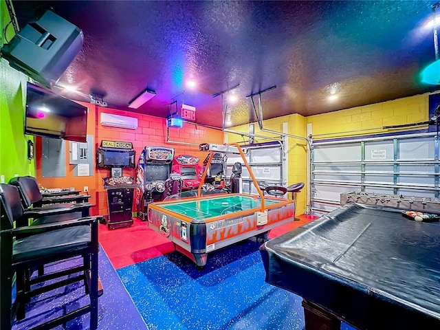 game room featuring a textured ceiling, an AC wall unit, and billiards