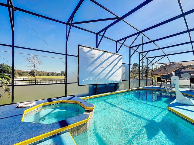 view of pool featuring glass enclosure and an in ground hot tub