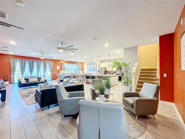 living room with ceiling fan, light hardwood / wood-style flooring, and a textured ceiling