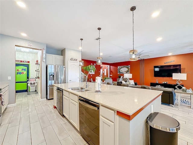 kitchen featuring pendant lighting, a kitchen island with sink, sink, appliances with stainless steel finishes, and white cabinetry