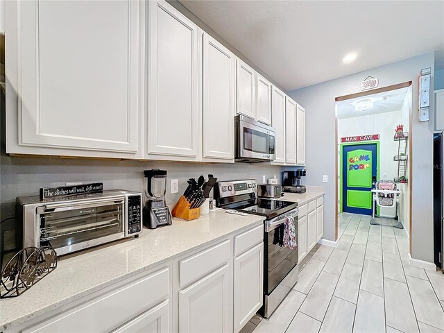 kitchen featuring white cabinets, light stone countertops, and appliances with stainless steel finishes