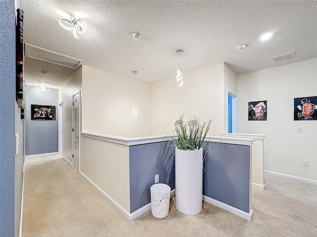 hallway with light carpet and a textured ceiling