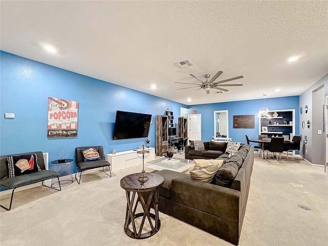 living room featuring ceiling fan, light colored carpet, and a textured ceiling