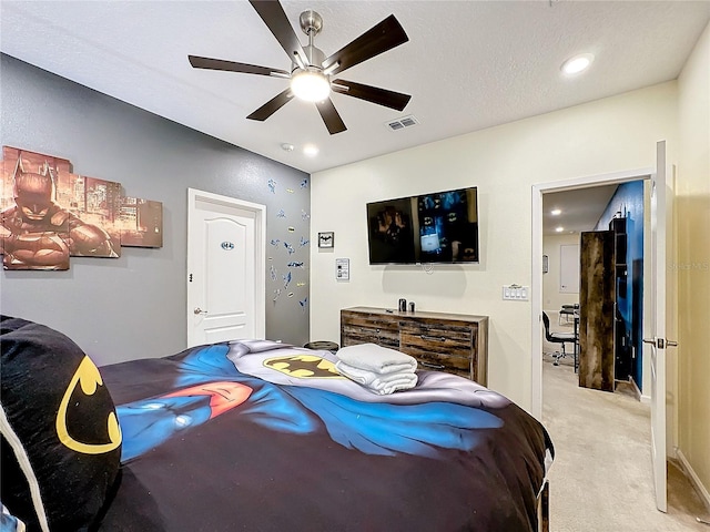 bedroom with a textured ceiling, light colored carpet, and ceiling fan