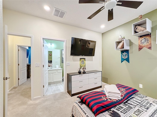 carpeted bedroom featuring ceiling fan, a textured ceiling, and ensuite bath