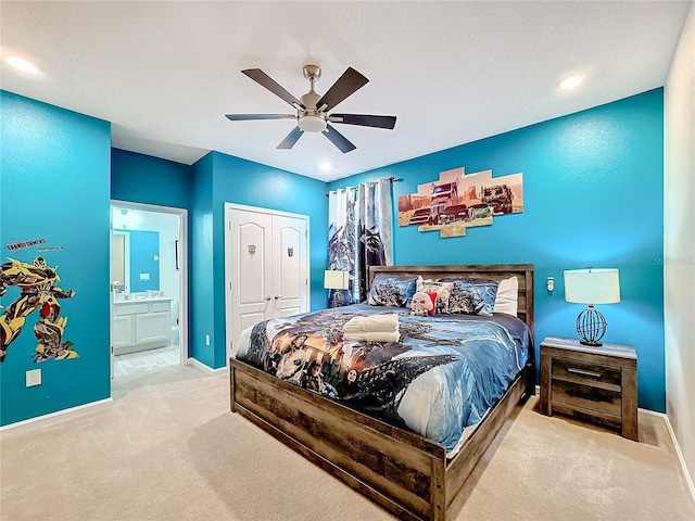 carpeted bedroom with a textured ceiling, ceiling fan, ensuite bathroom, and a closet