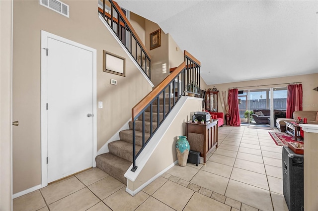 stairway featuring tile patterned flooring, a textured ceiling, and vaulted ceiling