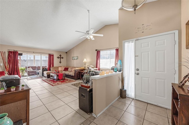 tiled foyer with ceiling fan, a textured ceiling, and high vaulted ceiling