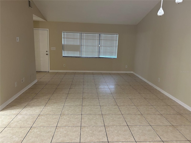 empty room with lofted ceiling and light tile patterned floors