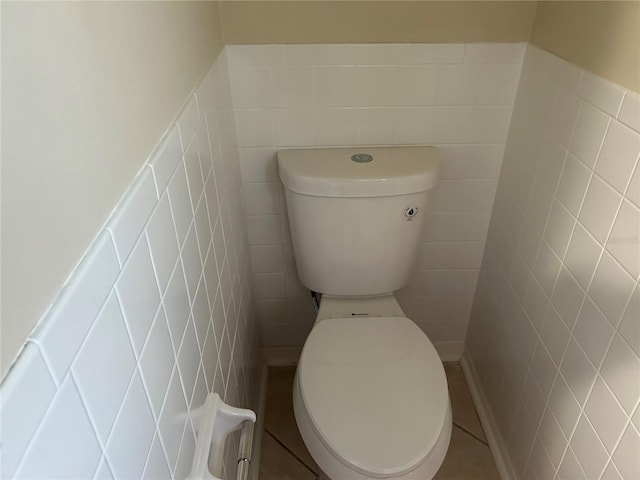 bathroom with toilet and tile walls