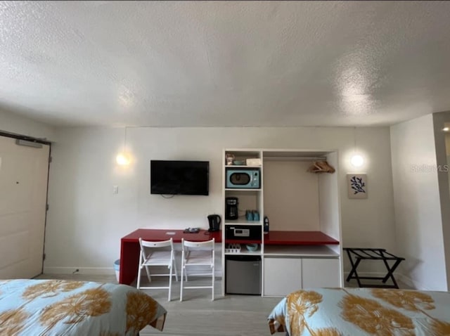 bedroom with a textured ceiling and light wood-type flooring