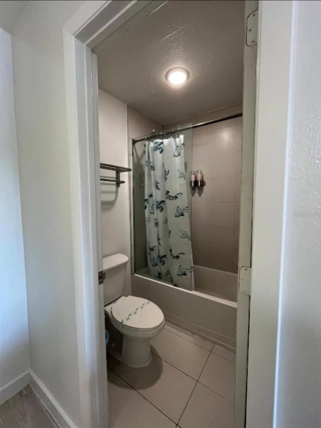 bathroom with tile patterned flooring, shower / bath combination with curtain, and toilet