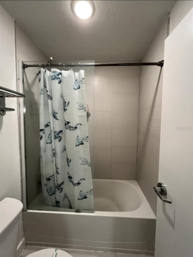 bathroom featuring shower / bath combo, a textured ceiling, and toilet