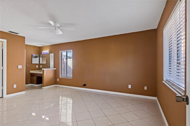 unfurnished room with ceiling fan, sink, light tile patterned flooring, and a textured ceiling