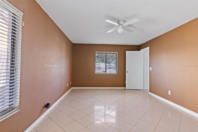 spare room with ceiling fan, light tile patterned floors, and a textured ceiling