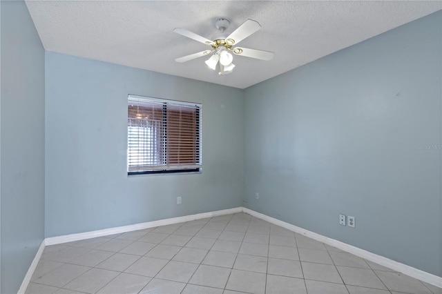 empty room featuring ceiling fan, light tile patterned flooring, and a textured ceiling