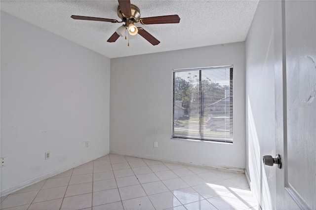 empty room featuring ceiling fan, light tile patterned floors, and a textured ceiling