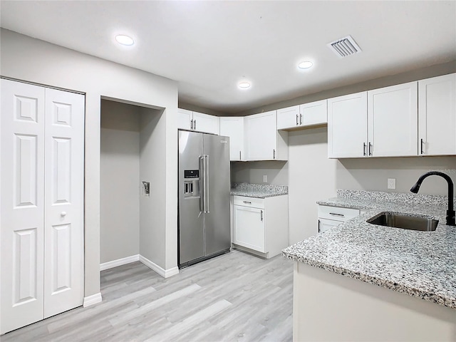 kitchen featuring light stone counters, high end fridge, sink, light hardwood / wood-style flooring, and white cabinetry