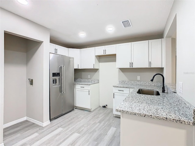 kitchen with light stone countertops, white cabinetry, light hardwood / wood-style flooring, and high end refrigerator