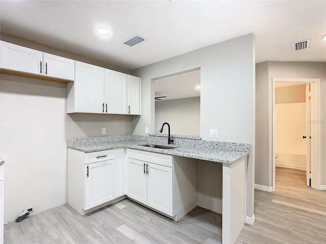 kitchen featuring light stone countertops, white cabinetry, sink, and light hardwood / wood-style flooring