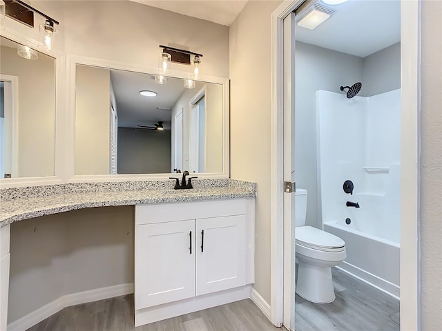 full bathroom featuring ceiling fan, hardwood / wood-style floors, toilet, shower / washtub combination, and vanity