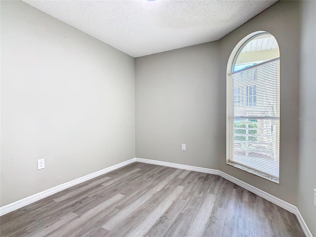 spare room featuring light hardwood / wood-style floors and a textured ceiling