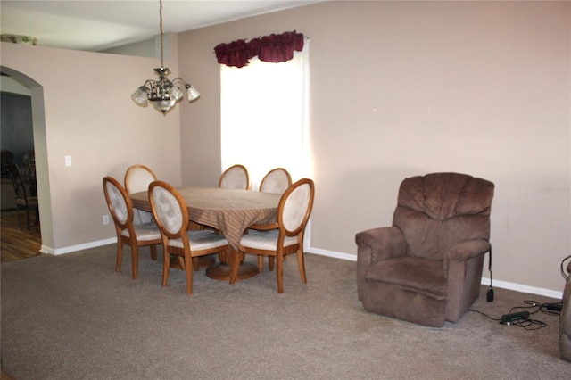 dining space featuring dark carpet and a notable chandelier