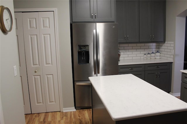 kitchen featuring stainless steel fridge, tasteful backsplash, a kitchen island, and light hardwood / wood-style floors