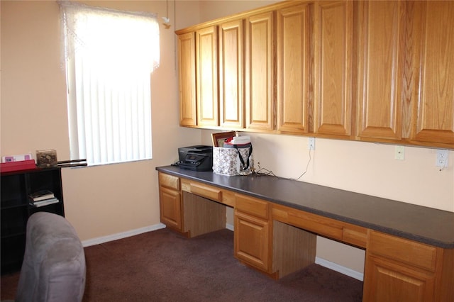 home office featuring built in desk and dark carpet